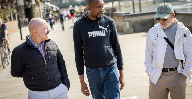 Three men walking together on a pavement.