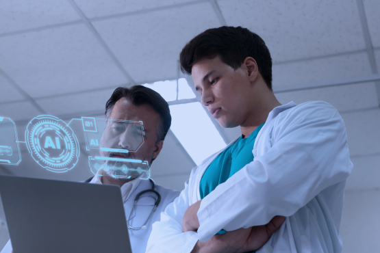 Two doctors looking at a laptop and an hologram that says 'AI'.