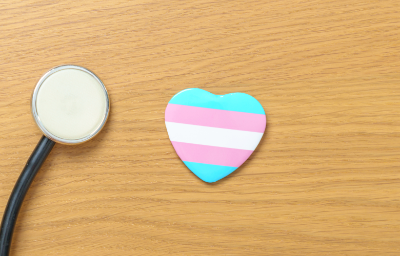 A stethoscope next to a heart with light blue, pink, and white stripes which are the colours of the transgender flag.
